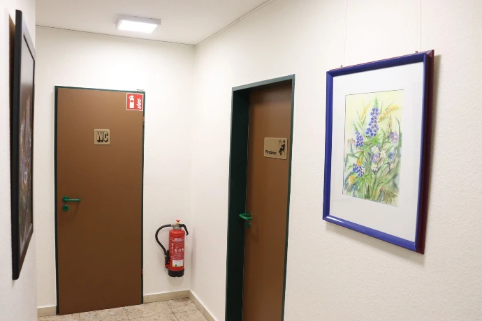 Der Flur der Praxis mit den Türen zu WC und Personalraum und einem gerahmten Blumenbild an der Wand.