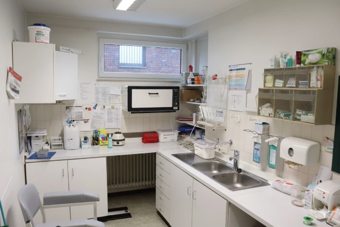 Der Funktionsraum: Arbeitsflächen mit Waschbecken, Sterilisator und den beschrifteten Materialfächern.